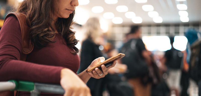 mulher olhando celular viagem atrasada no aeroporto apagão cibernético